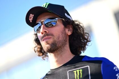 Alex Rins mengenakan topi Yamaha dan kacamata hitam di paddock MotoGP