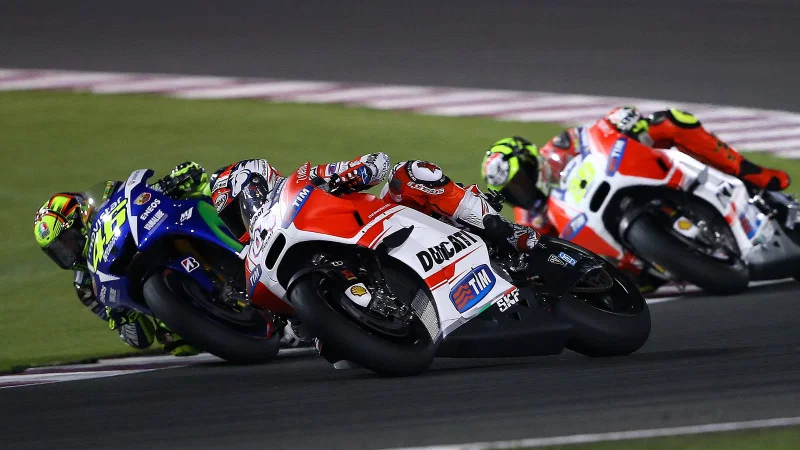 Andrea Dovizioso dengan Ducati GP15 bernomor 04 menikung bersama Valentino Rossi dan Andrea Iannone di GP Qatar 2015