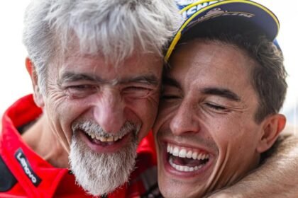 Gigi Dall’Igna dan Marc Marquez tersenyum sambil berpelukan dengan seragam Ducati.