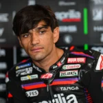 Jorge Martin mengenakan baju balap Aprilia Racing di depan latar logo tim.