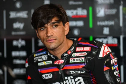 Jorge Martin mengenakan baju balap Aprilia Racing di depan latar logo tim.