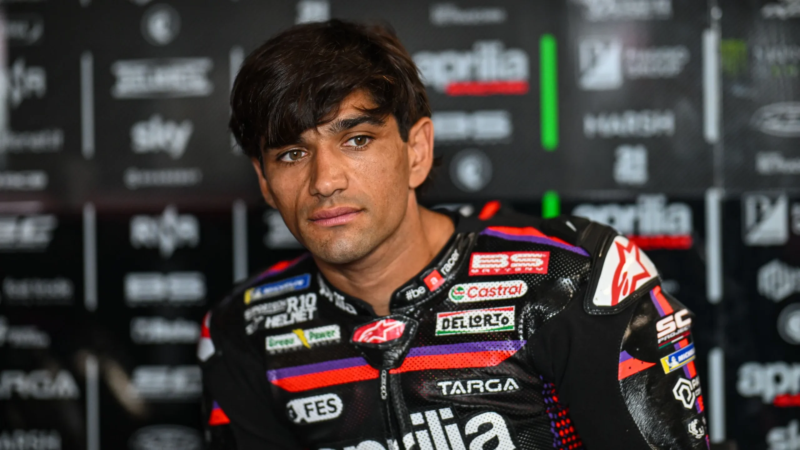 Jorge Martin mengenakan baju balap Aprilia Racing di depan latar logo tim.