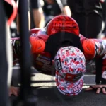 Marc Marquez melakukan push-up di grid Motegi dengan mengenakan helm dan baju balap Ducati.
