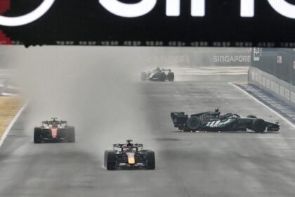 Max Verstappen melaju melewati mobil George Russell yang mengalami kecelakaan di lintasan basah Marina Bay