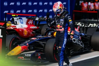 Max Verstappen mengangkat kepalan tangan di samping mobil Red Bull setelah meraih pole di Sepang